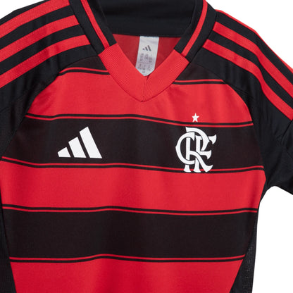 Close-up da camisa infantil do Flamengo, listrada em vermelho e preto, com escudo do time e logo Adidas em branco no peito.