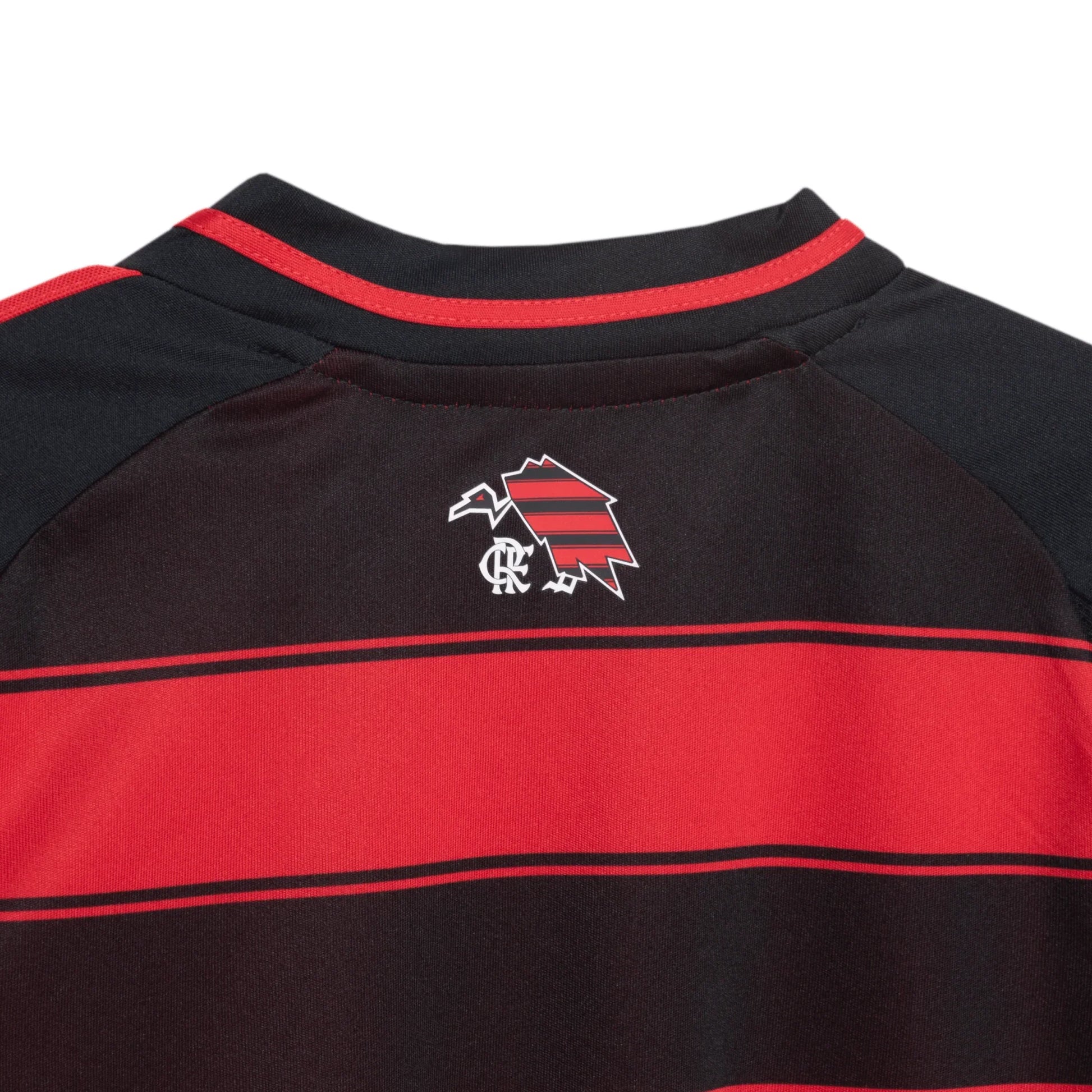 Parte superior traseira de uma camisa infantil listrada em vermelho e preto. Emblema nas costas: pássaro listrado e monograma branco.
