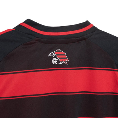 Parte superior traseira de uma camisa infantil listrada em vermelho e preto. Emblema nas costas: pássaro listrado e monograma branco.