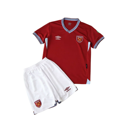 Kit infantil West Ham I 25/26, camisa vermelha bordô e shorts brancos com escudo West Ham e logo Umbro, fundo preto.