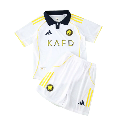 Kit infantil Al Nassr branco com gola azul marinho, listras e logos amarelos, shorts brancos com faixas amarelas.
