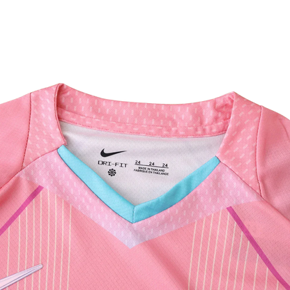 Vista interna da gola de uma camisa de futebol infantil rosa com detalhes azuis. Possui logo Nike, DRI-FIT e tamanho 24.