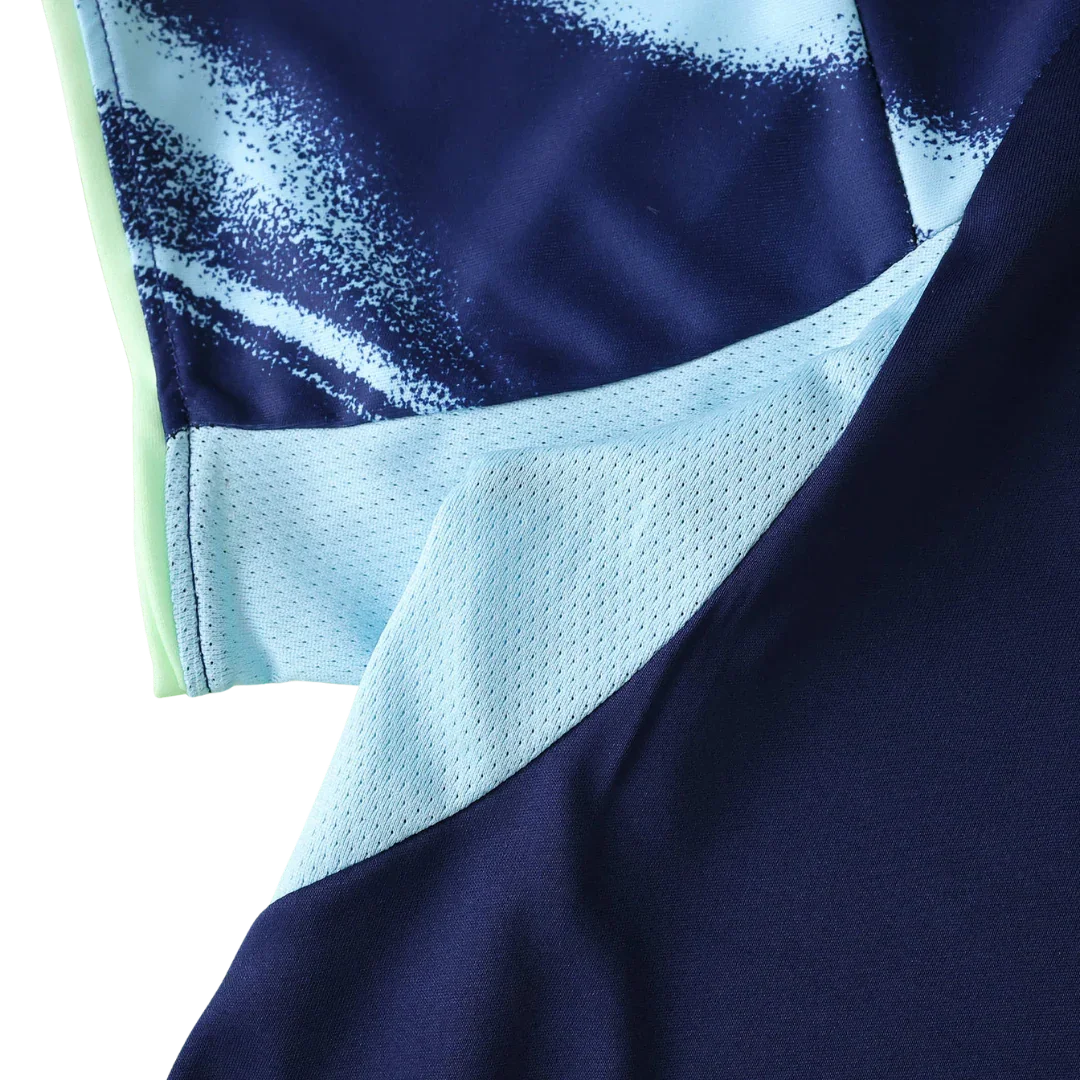 Detalhe próximo de camisa esportiva azul marinho com estampa abstrata azul claro e painéis em tela azul bebê, lateral verde-limão.