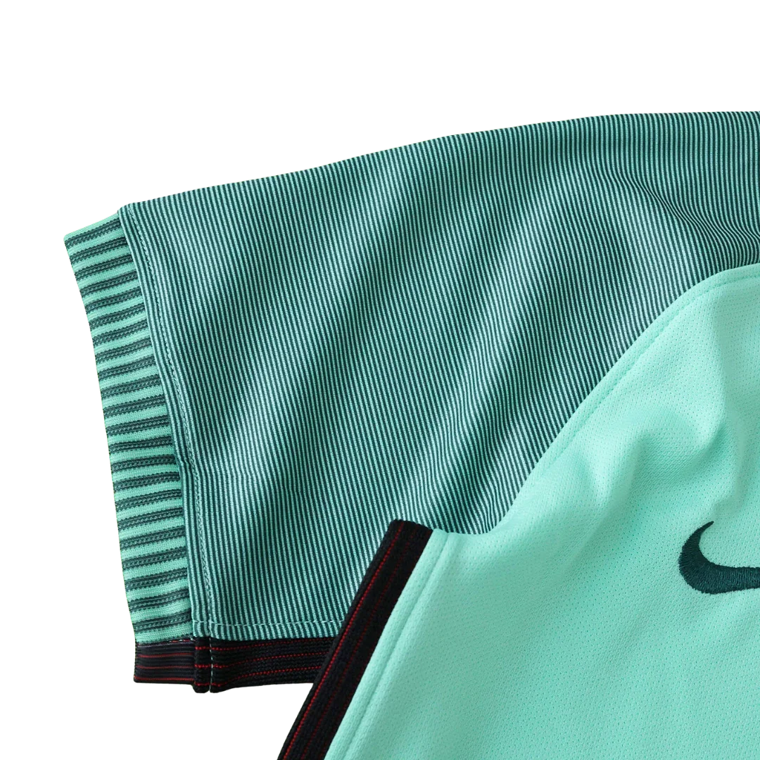 Detalhe de camisa de futebol infantil verde-água com listras verticais, gola preta com detalhes vermelhos e logo Nike preto.