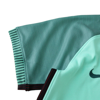 Detalhe de camisa de futebol infantil verde-água com listras verticais, gola preta com detalhes vermelhos e logo Nike preto.