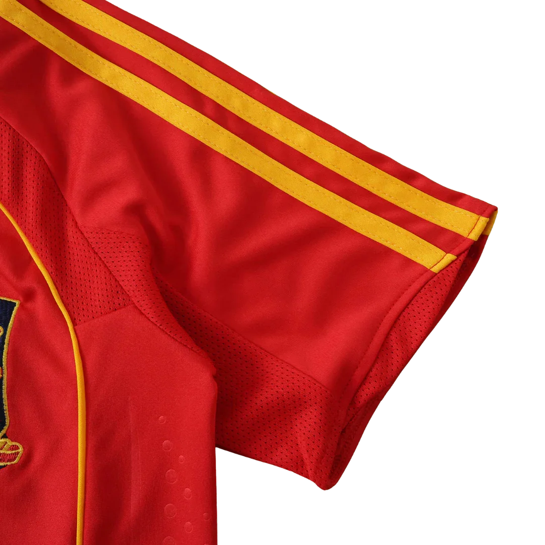 Camisa de futebol infantil vermelha com três listras amarelas na manga e painéis de malha. Detalhe de costura amarela e brasão bordado.