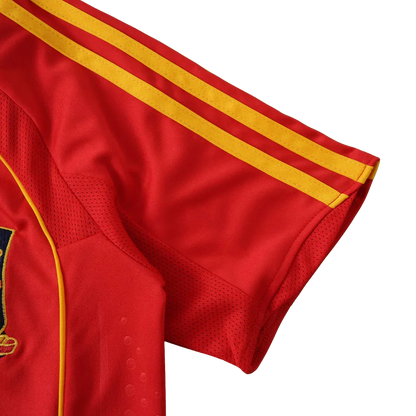 Camisa de futebol infantil vermelha com três listras amarelas na manga e painéis de malha. Detalhe de costura amarela e brasão bordado.