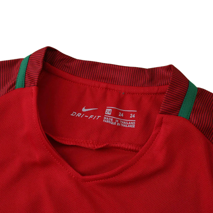 Detalhe da gola interna de camisa infantil vermelha com listras, logo Nike Dri-Fit e etiqueta de fabricação da Tailândia.