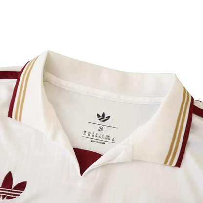 Close-up da gola de camisa infantil Adidas branca com detalhes em bordô e dourado. Rótulo interno com tamanho 24 e 'Made in Vietnam'.