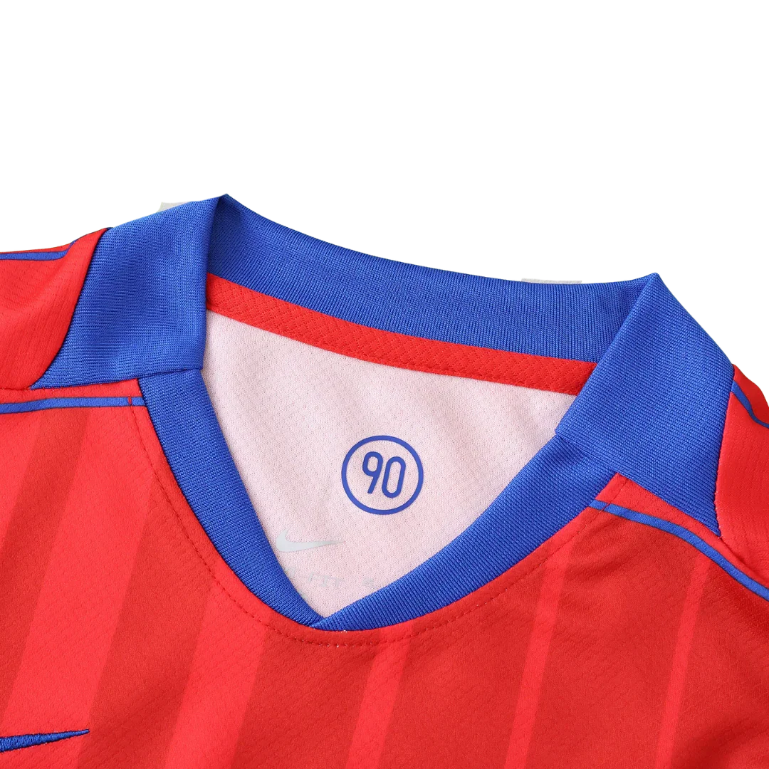 Camisa de futebol infantil vermelha com listras e gola azul. Detalhe da gola interna com '90' em círculo e logo Nike.