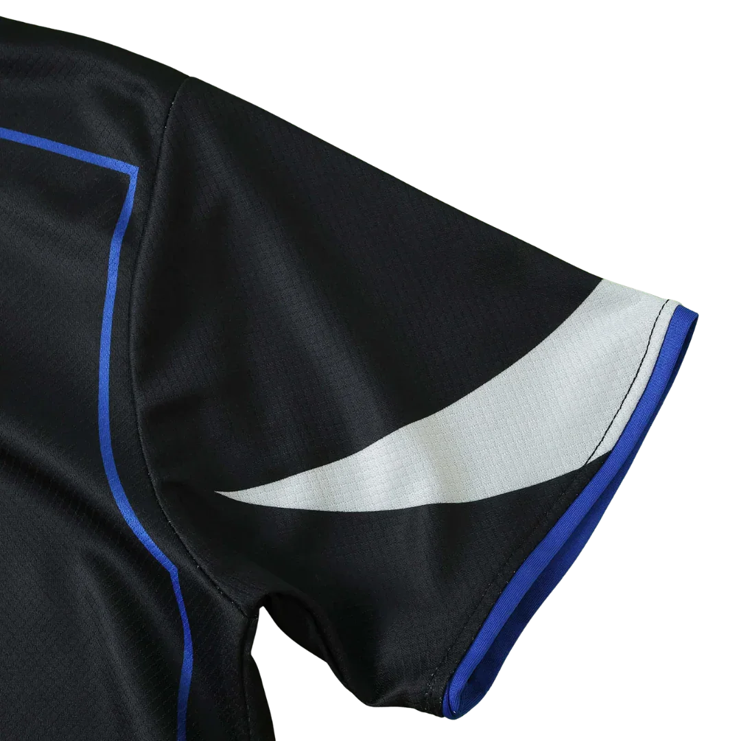 Manga de camisa infantil preta com detalhe branco e azul. Tecido texturizado e costura visível.