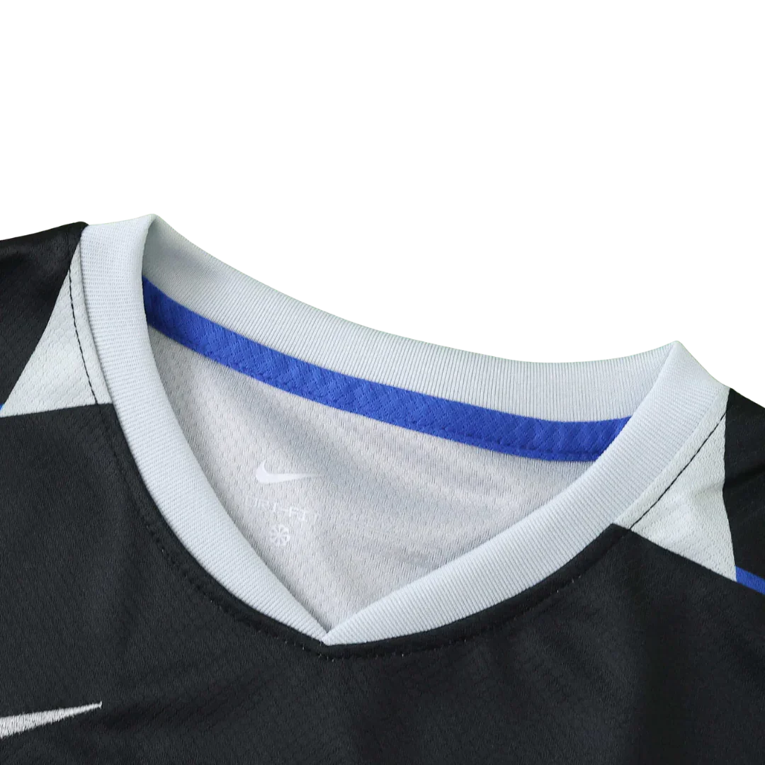 Close-up da gola V de uma camisa de futebol infantil preta, com gola cinza claro e faixa azul interna. Logo Nike e Dry-Fit visíveis.