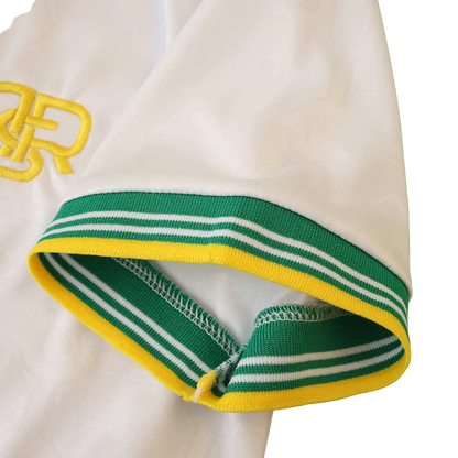 Manga de camisa infantil branca com punho listrado verde, branco e amarelo. Detalhe de bordado amarelo na camisa.