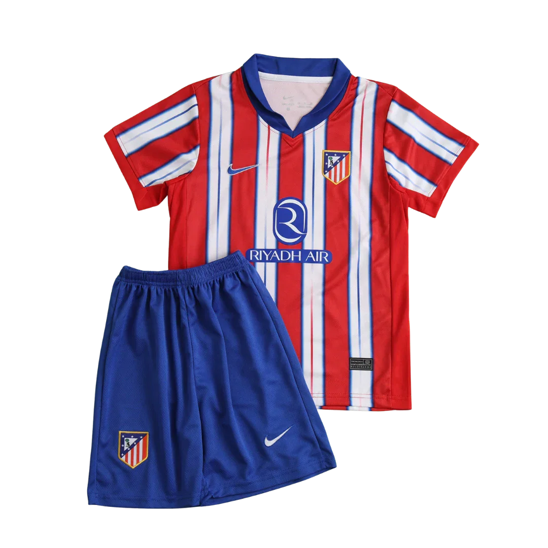 Kit infantil Atletico de Madrid 24/25 com camisa listrada em vermelho, branco e azul, shorts azuis. Inclui escudos e logos Nike e Riyadh Air.