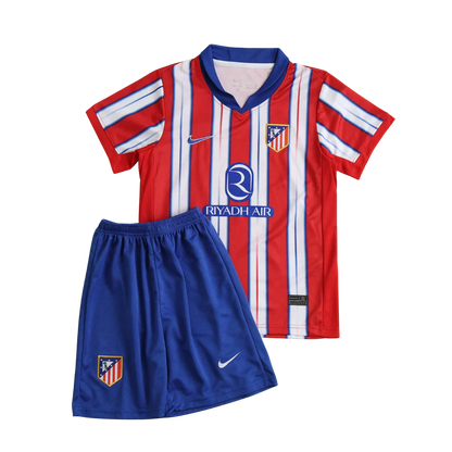 Kit infantil Atletico de Madrid 24/25 com camisa listrada em vermelho, branco e azul, shorts azuis. Inclui escudos e logos Nike e Riyadh Air.