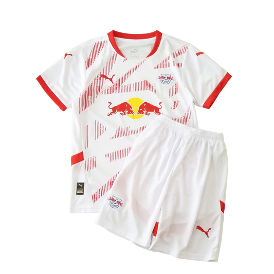 Kit de futebol infantil Leipzig 24/25 branco com detalhes e listras vermelhas, escudo do time e logo Puma visíveis na camisa e shorts.