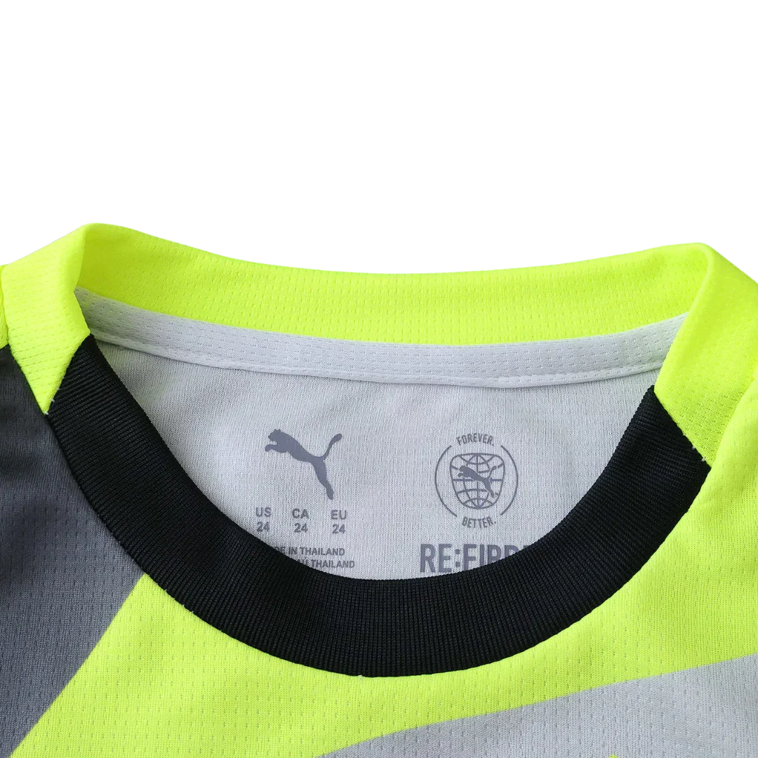 Detalhe da gola de uma camisa infantil Puma, com cores amarelo fluorescente, preto e cinza. Etiqueta interna visível com logo Puma e informações de tamanho.