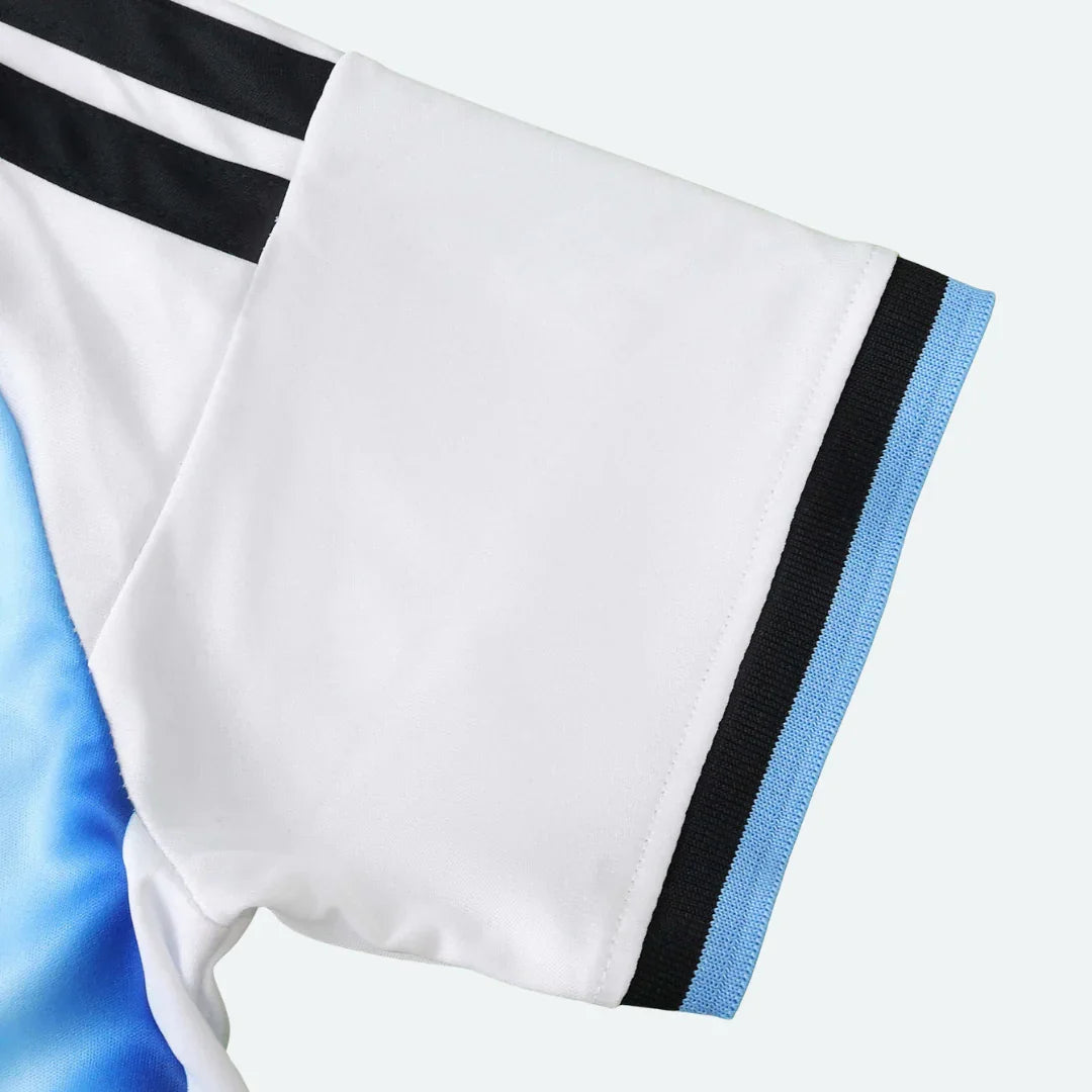 Close-up da manga de uma camisa infantil branca com detalhes em preto e azul claro na barra.