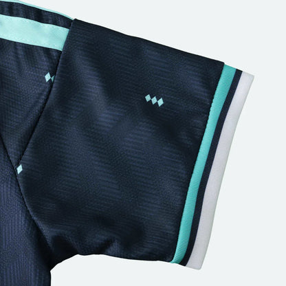 Detalhe da manga de uma camisa esportiva azul marinho com detalhes em verde água e acabamento listrado.