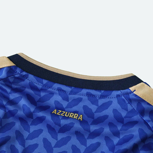 Detalhe da gola interna de camisa azul com a palavra AZZURRA dourada e padrão de folhas.