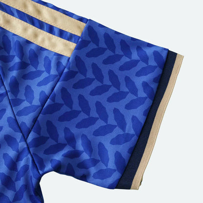 Close-up da manga de uma camisa azul vibrante com padrão de folhas em tom de azul mais escuro.