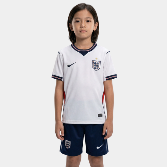 Menino vestindo o kit infantil da Inglaterra, com camisa branca, detalhes em azul marinho e calção azul.