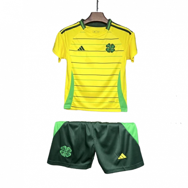 Kit infantil Celtic II 24/25 amarelo e verde. Camisa com listras horizontais escuras, shorts verde. Escudos do Celtic e Adidas visíveis.