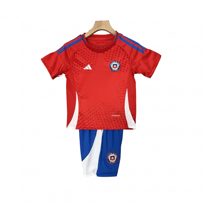 Kit infantil do Chile para a temporada 24/25, com camisa vermelha e shorts azuis, pendurado em cabide.