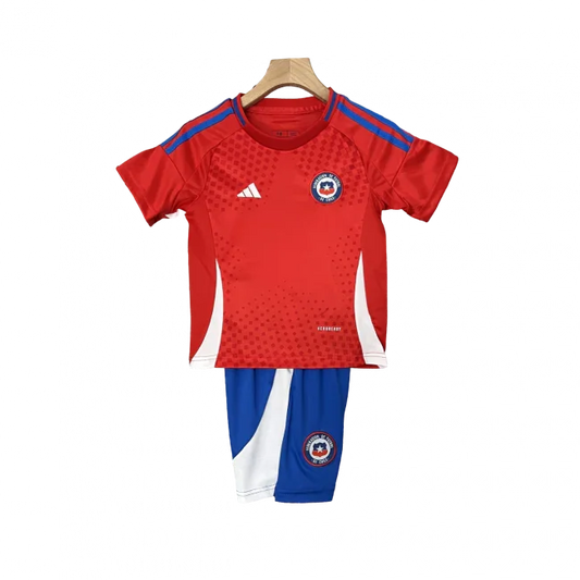 Kit infantil do Chile para a temporada 24/25, com camisa vermelha e shorts azuis, pendurado em cabide.