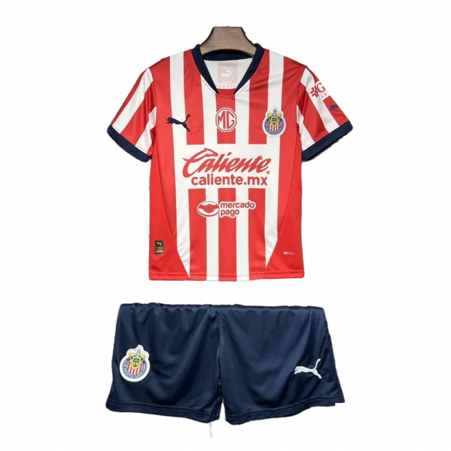 Kit infantil Chivas I 24/25 com camisa listrada vermelha e branca, shorts azul marinho, escudos e logos visíveis.