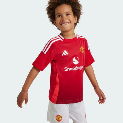 Mini Mantos infantil oficial kit camisa Manchester United, criança sorridente vestindo o uniforme de futebol do time