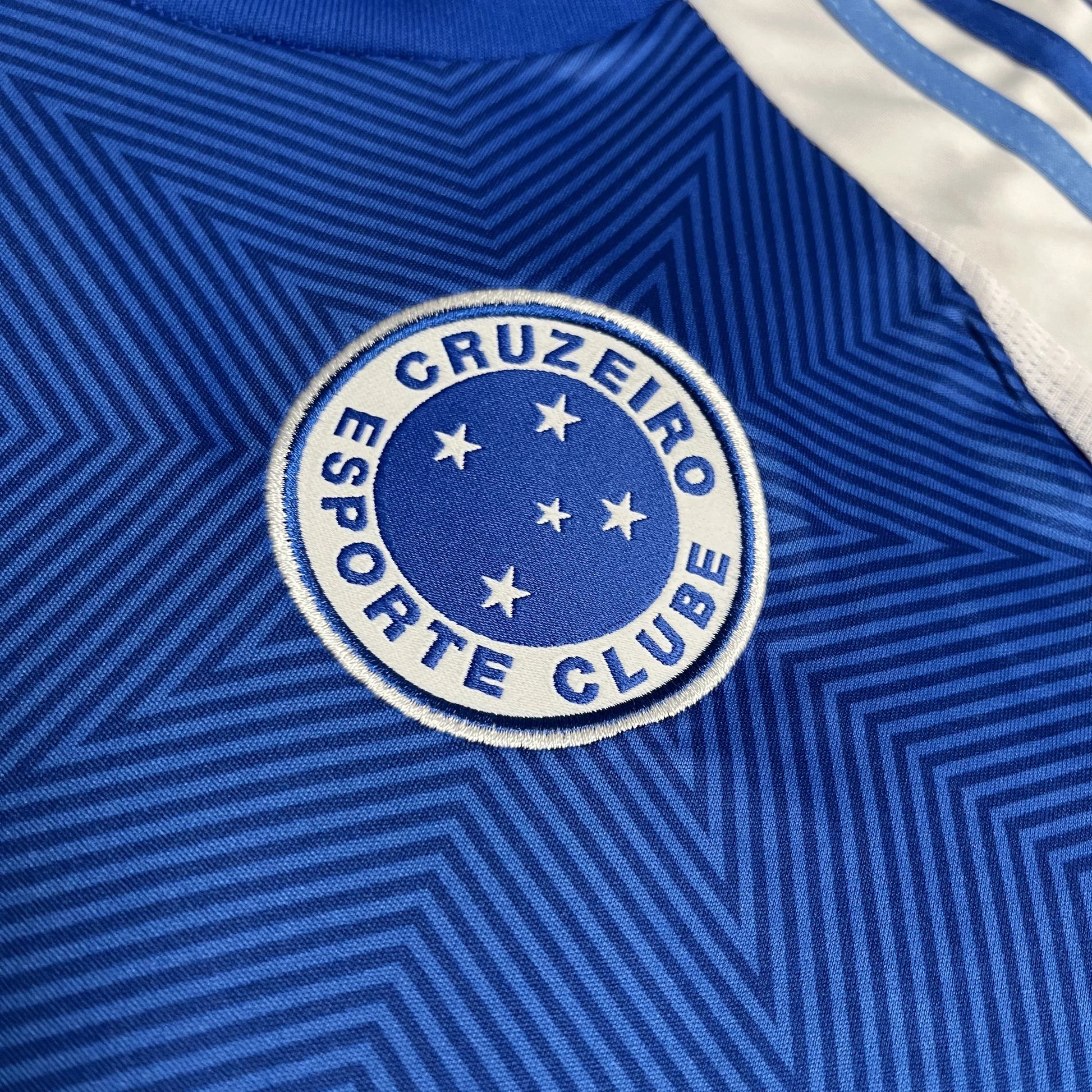 Detalhe da camisa oficial infantil do Cruzeiro, kit Mini Mantos. Distintivo bordado azul com estrelas brancas