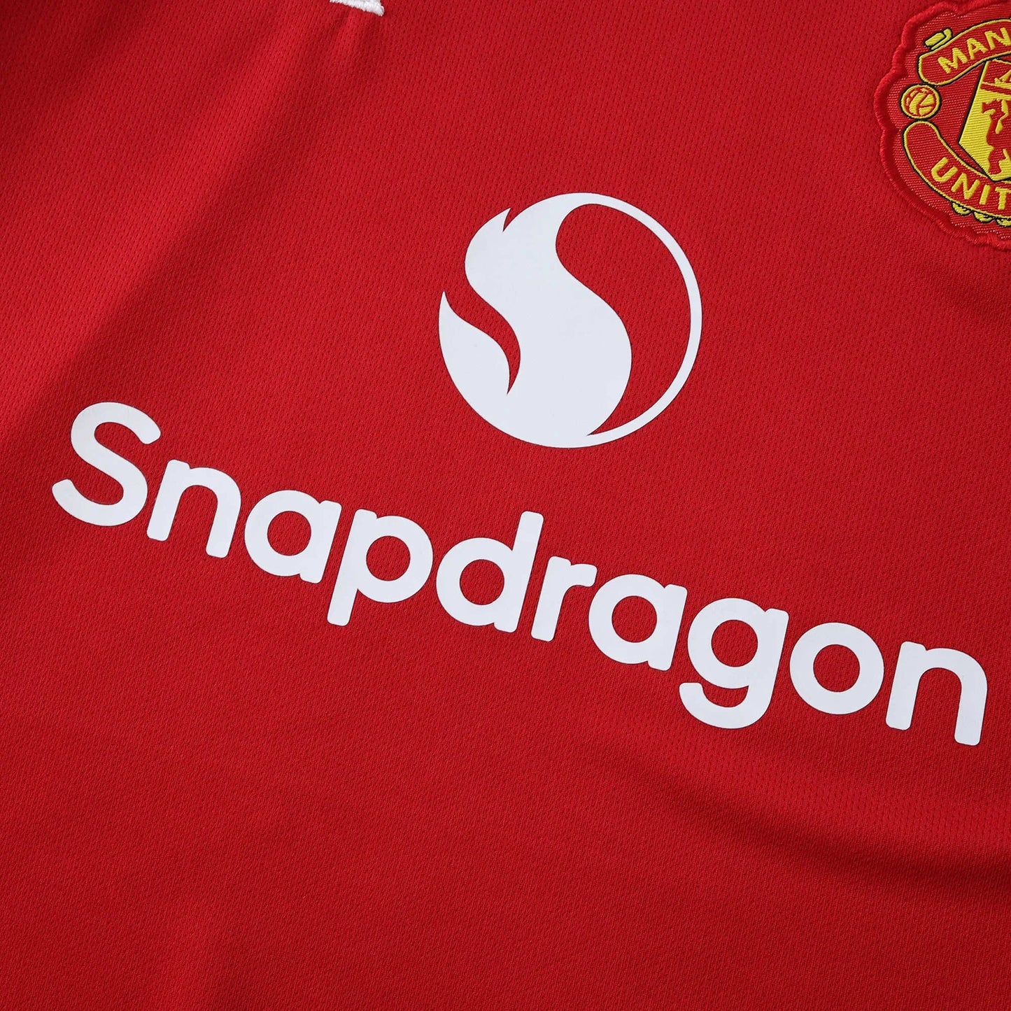 Camisa oficial Manchester United infantil, kit Mini Mantos. Detalhe da camisa vermelha com logo Snapdragon