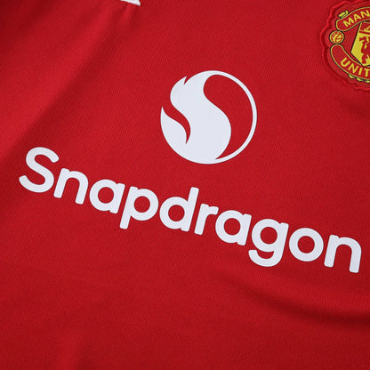 Camisa oficial Manchester United infantil, kit Mini Mantos. Detalhe da camisa vermelha com logo Snapdragon