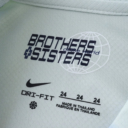 Detalhe da etiqueta interna em tecido verde-claro de camisa esportiva Nike Dri-Fit, com a frase 'Brothers & Sisters Of The World'.