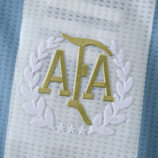 Camisa Argentina infantil oficial, kit Mini Mantos. Detalhe do badge AFA dourado com 3 estrelas