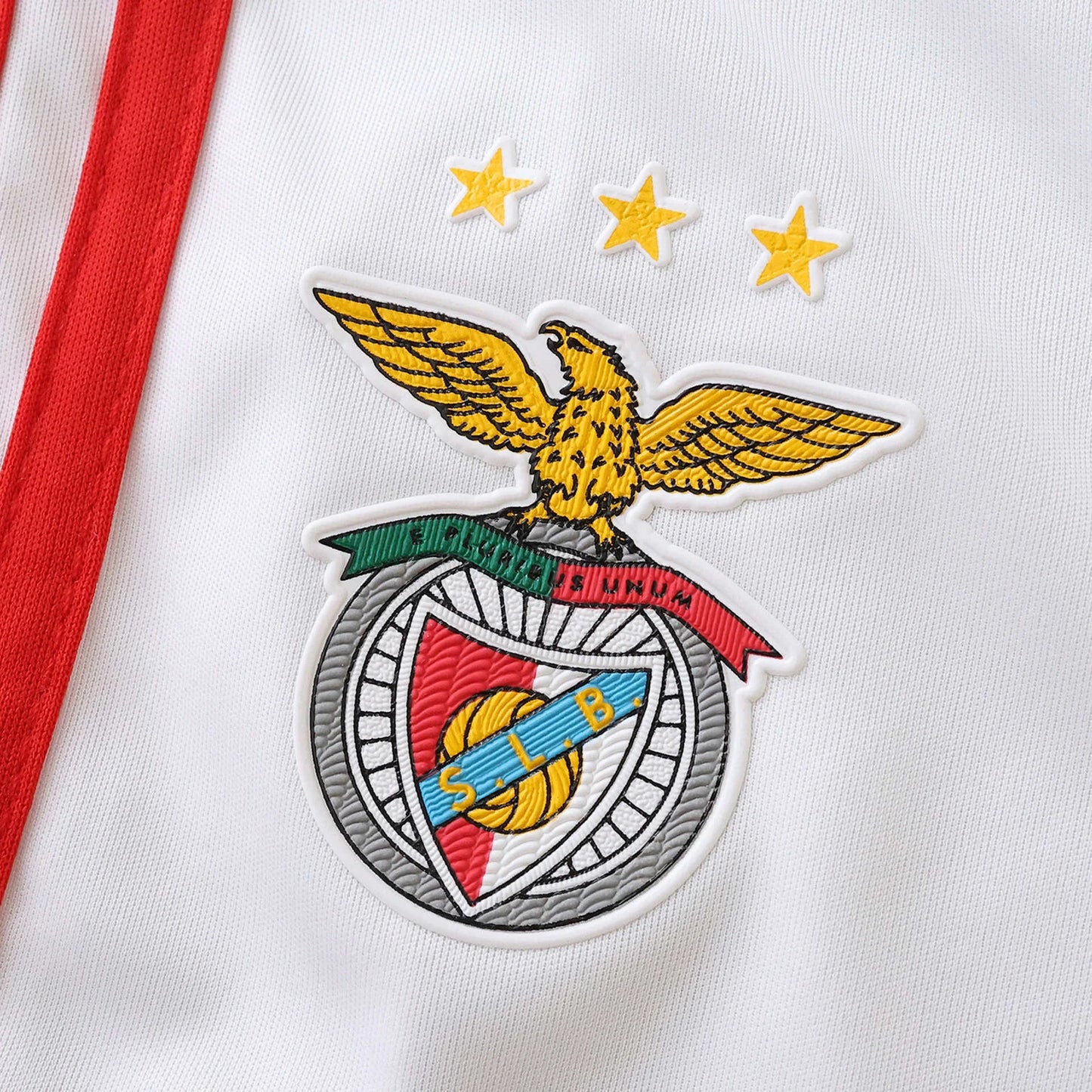 Detalhe da camisa infantil oficial do Benfica, kit Mini Mantos com escudo e estrelas em destaque