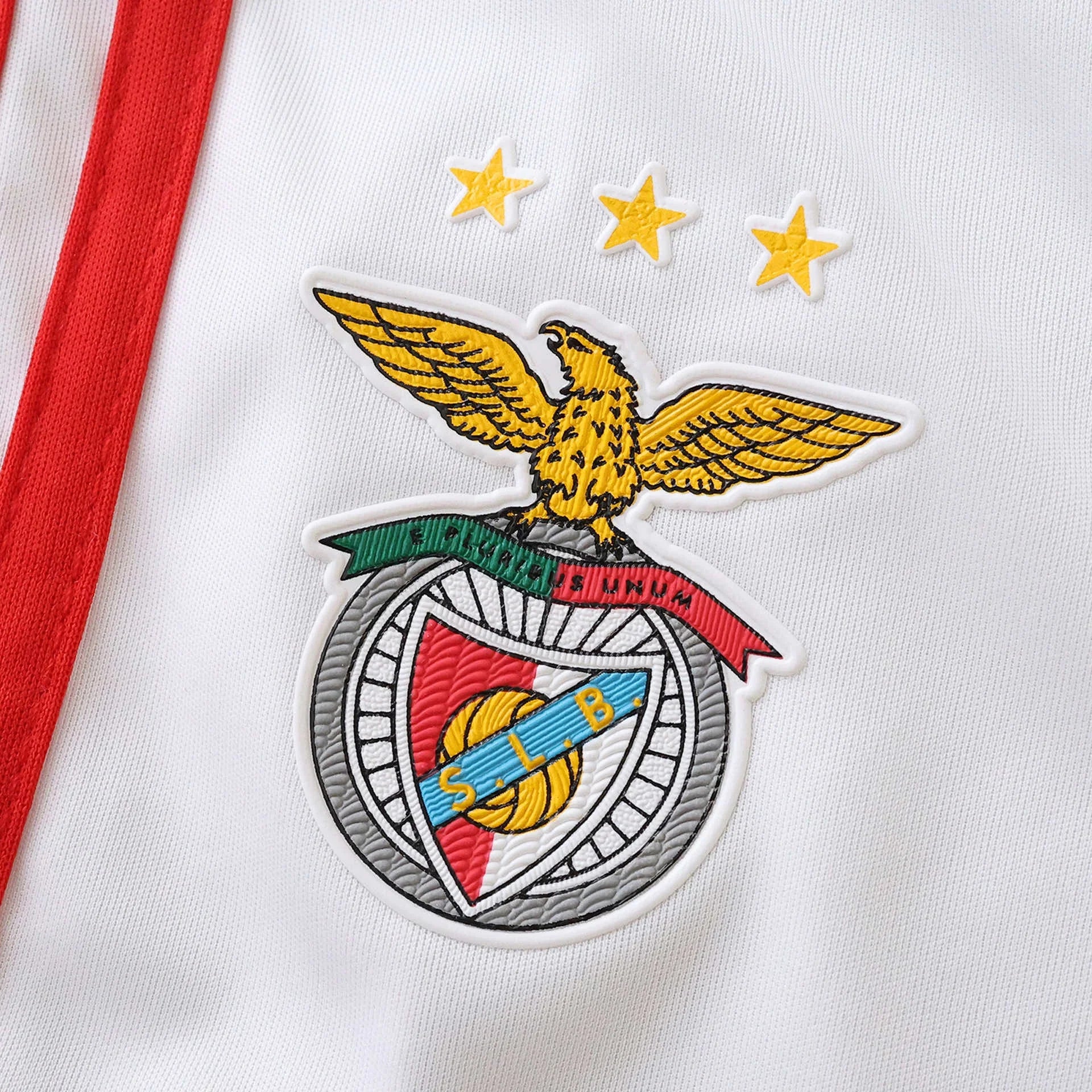 Detalhe da camisa infantil oficial do Benfica, kit Mini Mantos com escudo e estrelas em destaque