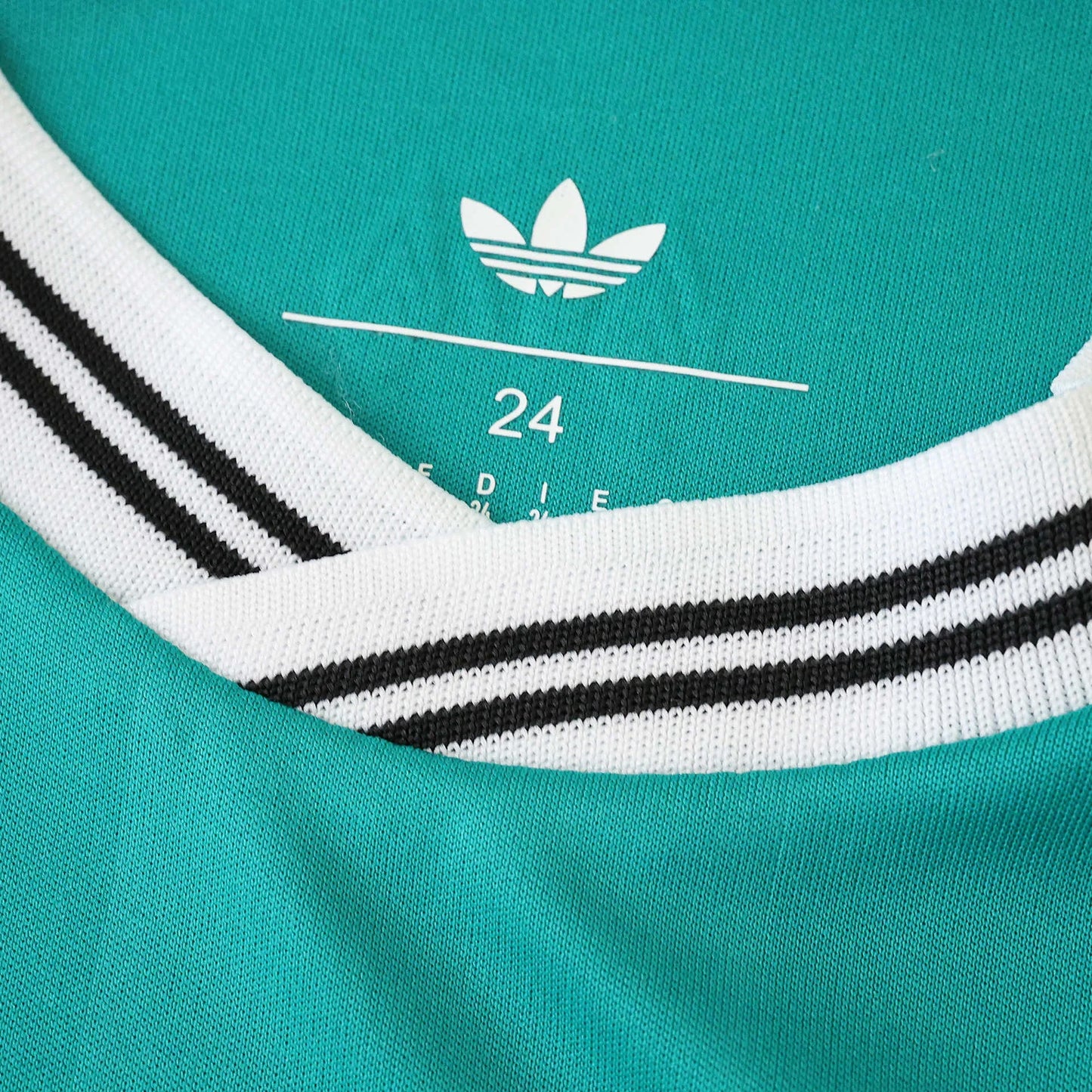 Gola de camisa infantil verde-água com detalhes brancos e listras pretas. Logo Adidas Trefoil e número 24 visíveis no interior.