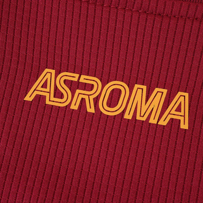 Foto em close da camisa infantil AS Roma vermelha com textura listrada vertical e o logo ASROMA em laranja. Detalhe da costura superior.