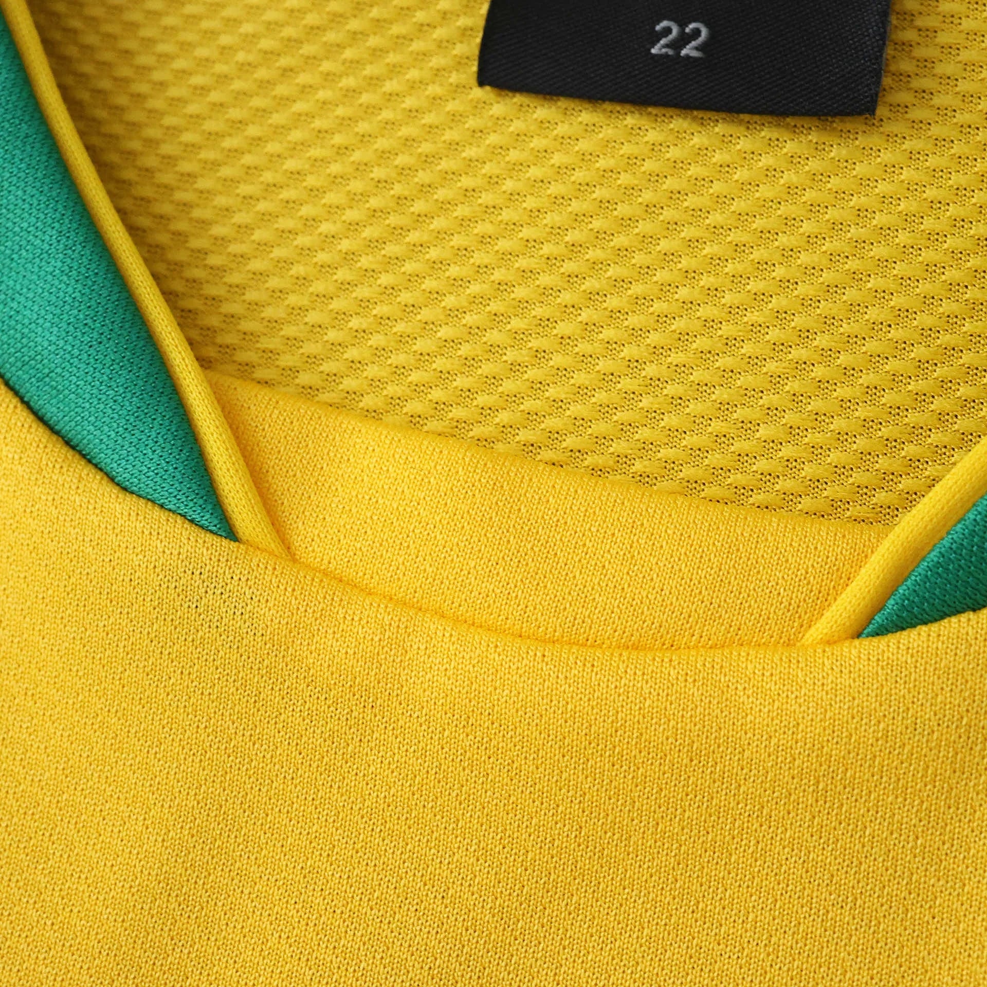 Camisa oficial Brasil Mini Mantos kit infantil, amarela e verde. Detalhe da gola, tecido furadinho e malha