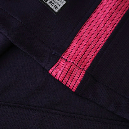 Close-up de camisa infantil azul marinho com listra vertical rosa e linhas pretas. Detalhe de costuras e etiqueta '2016'.