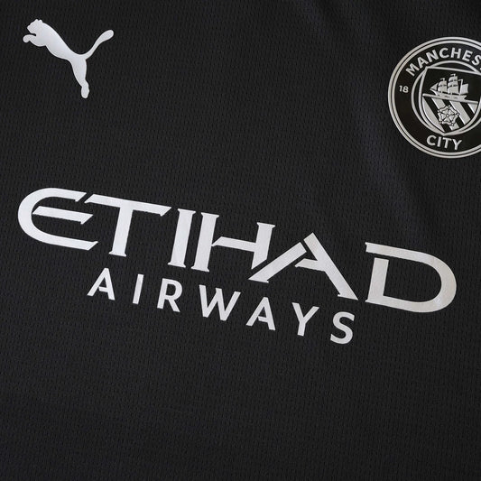 Camisa de futebol preta do Manchester City com logos da Puma, Etihad Airways e o escudo do clube em branco/prata.
