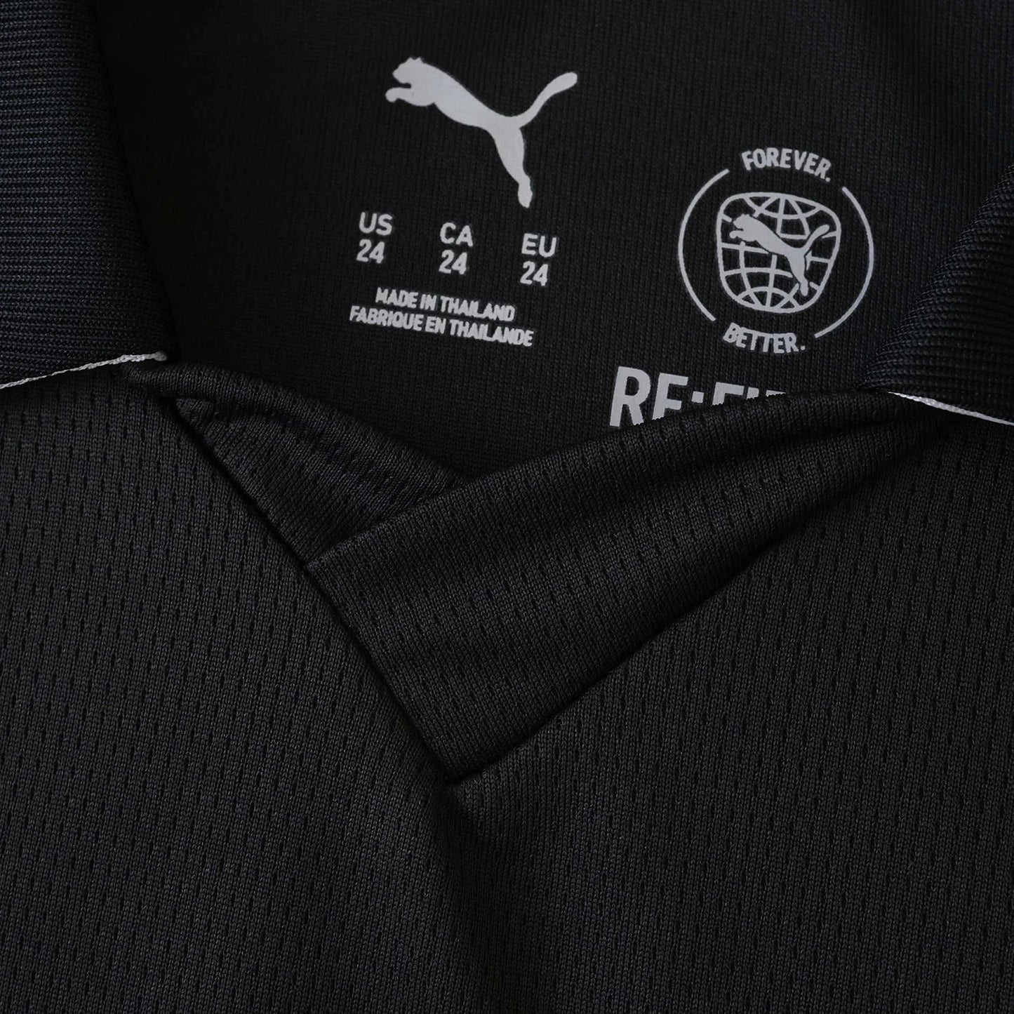 Foto em close da etiqueta interna de uma camisa preta Puma. Mostra o logo Puma, tamanhos (US/CA/EU 24) e 'MADE IN THAILAND'.