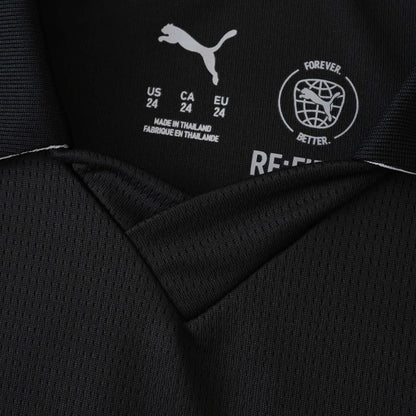 Foto em close da etiqueta interna de uma camisa preta Puma. Mostra o logo Puma, tamanhos (US/CA/EU 24) e 'MADE IN THAILAND'.
