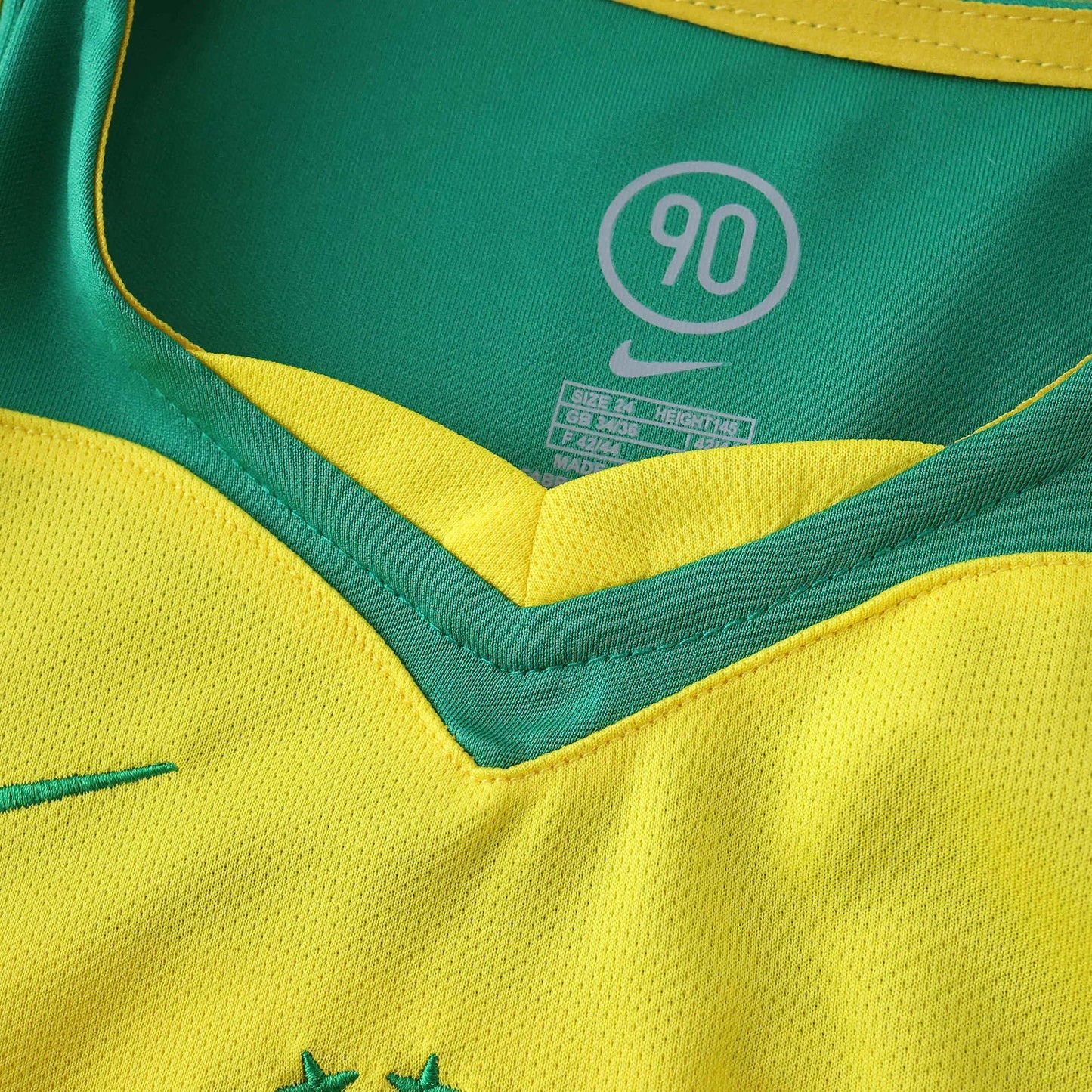 Camisa oficial Brasil infantil Mini Mantos kit Nike: gola verde e amarela com etiqueta de tamanho e símbolo 90