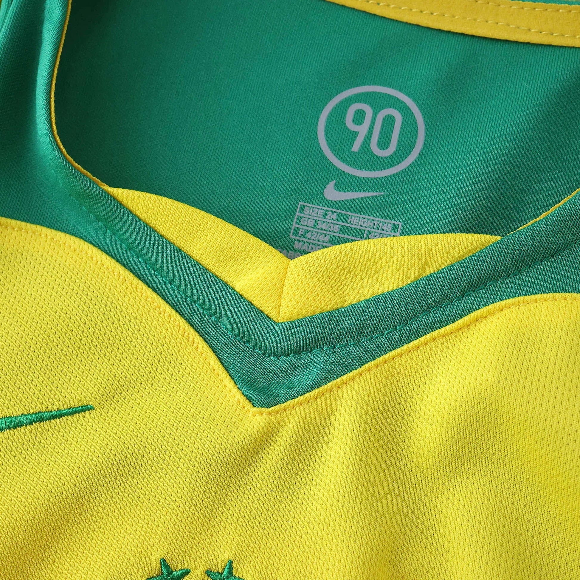 Camisa oficial Brasil infantil Mini Mantos kit Nike: gola verde e amarela com etiqueta de tamanho e símbolo 90