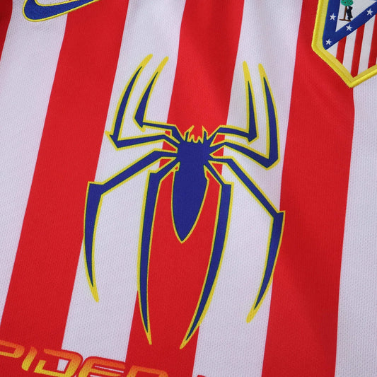 Camisa infantil listrada em vermelho e branco com logo azul de aranha amarela. Escudo do Atlético de Madrid e logo Nike visíveis.