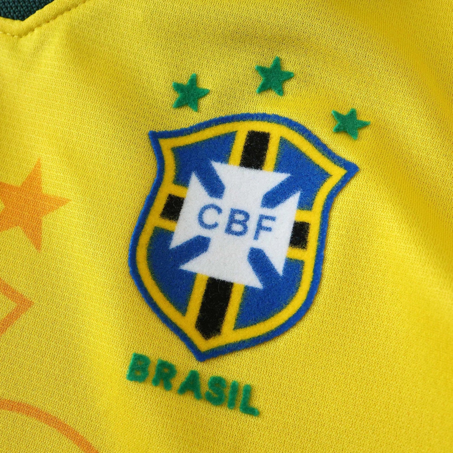 Camisa infantil oficial Brasil Mini Mantos, kit amarela. Detalhe do escudo CBF com estrelas