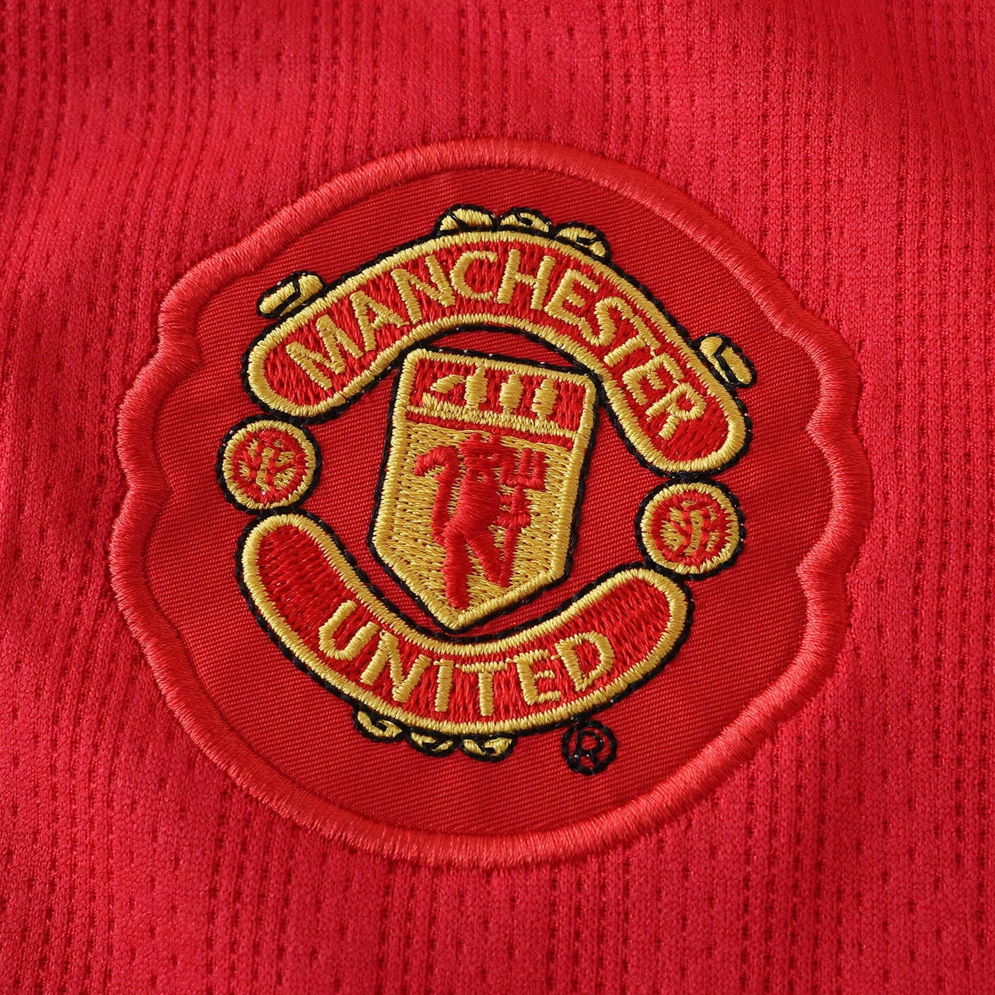 Camisa oficial Manchester United infantil, kit Mini Mantos. Detalhe bordado do escudo em vermelho e dourado
